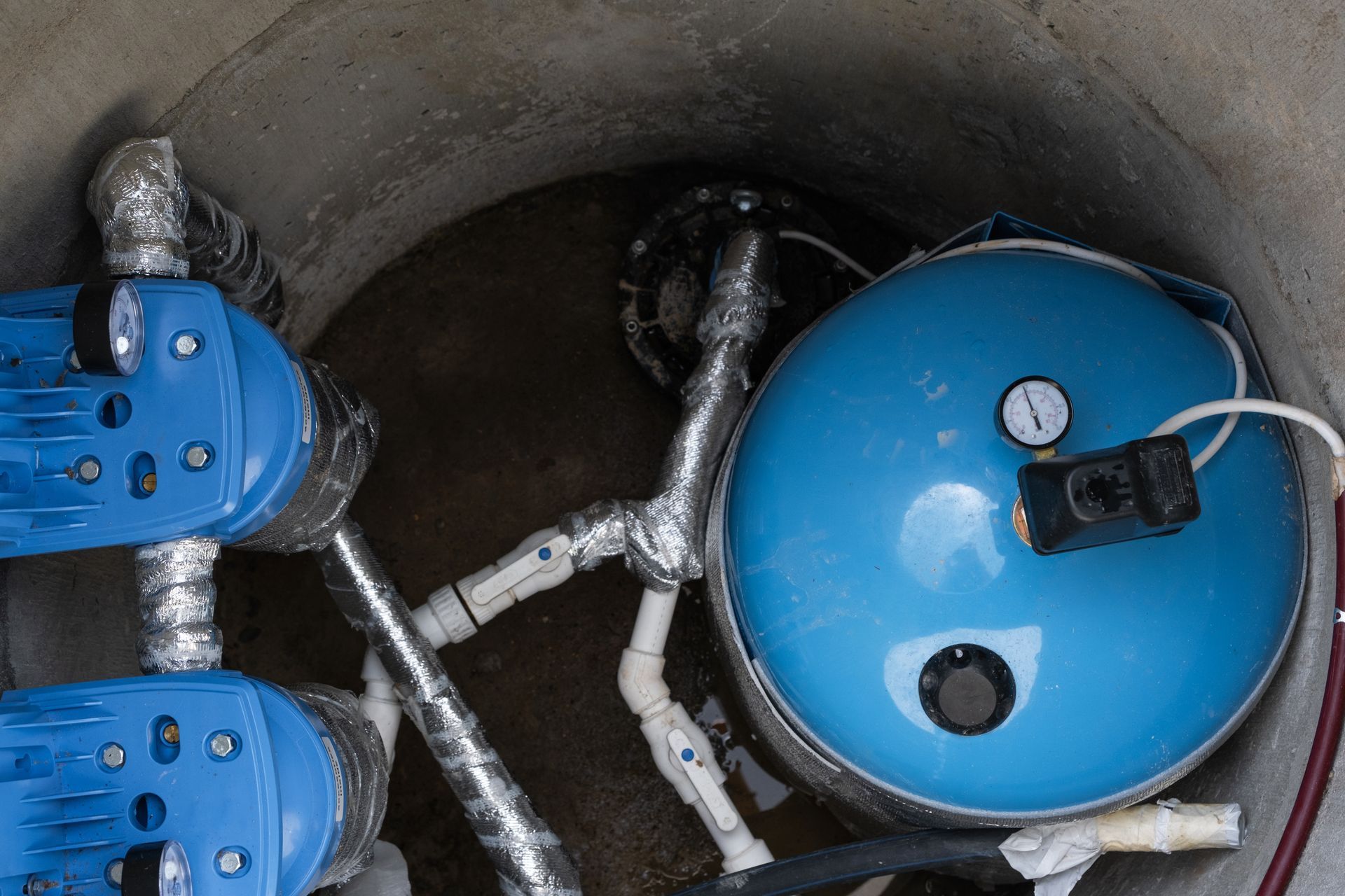 Overhead view of a water pump system with blue pressure tank, valves, and plumbing. Overhead view of a water pump system with blue pressure tank, valves, and plumbing.