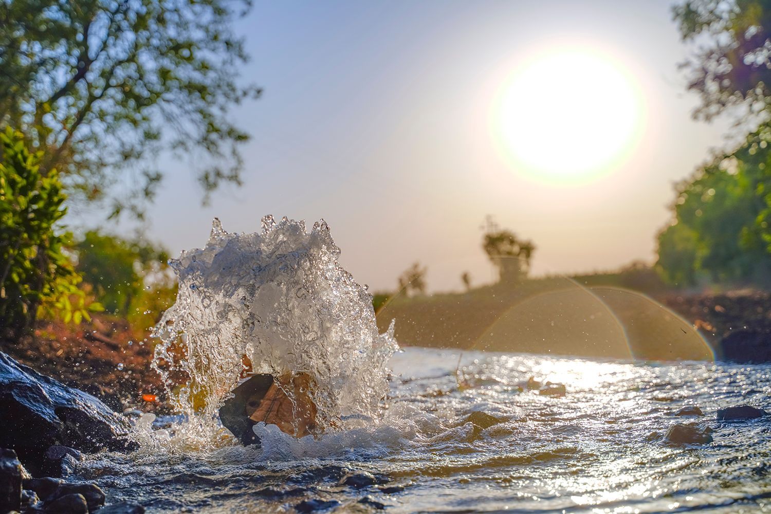 Water bursts from a newly drilled ground opening as sunlight shines over the scene. Water bursts from a newly drilled ground opening as sunlight shines over the scene.
