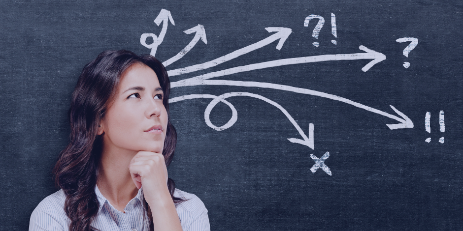 Woman pondering, with arrows and symbols drawn on a blackboard behind her.