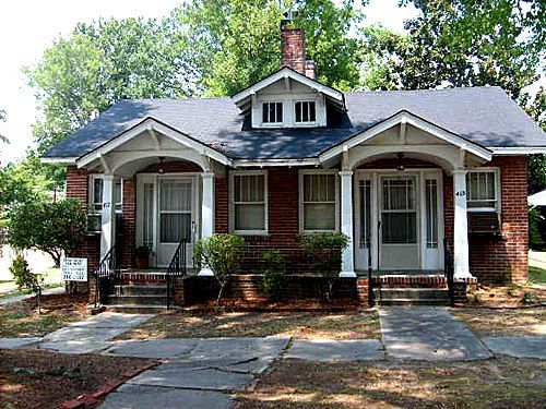 A small brick house with a porch and stairs