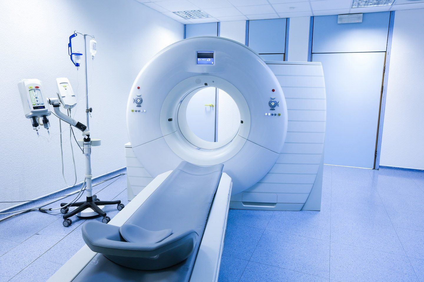 Una stanza luminosa e sterile dotata di una macchina per la tomografia computerizzata (TC) con lettino per il paziente e supporto per l'iniettore di mezzo di contrasto.