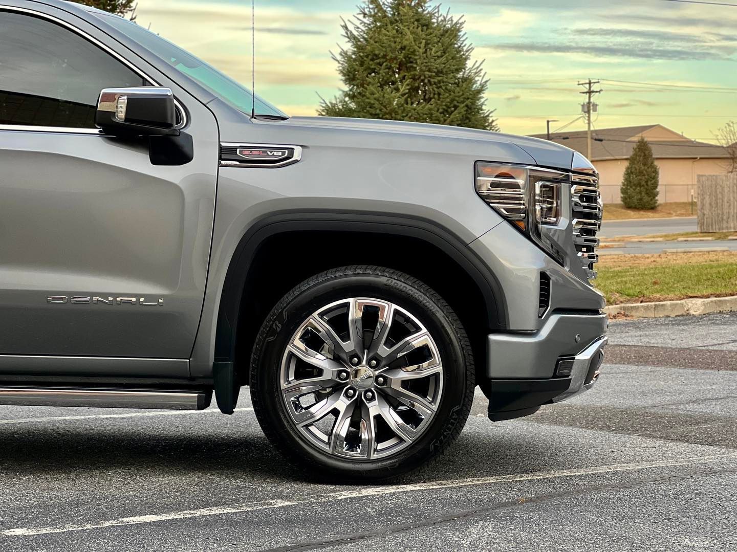 A silver gmc sierra is parked in a parking lot.