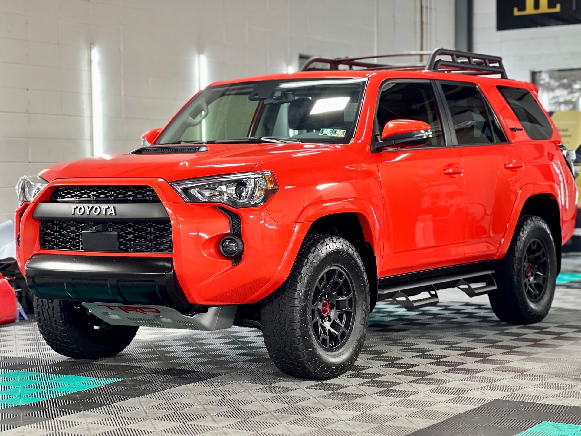A red toyota 4runner is parked in a garage.