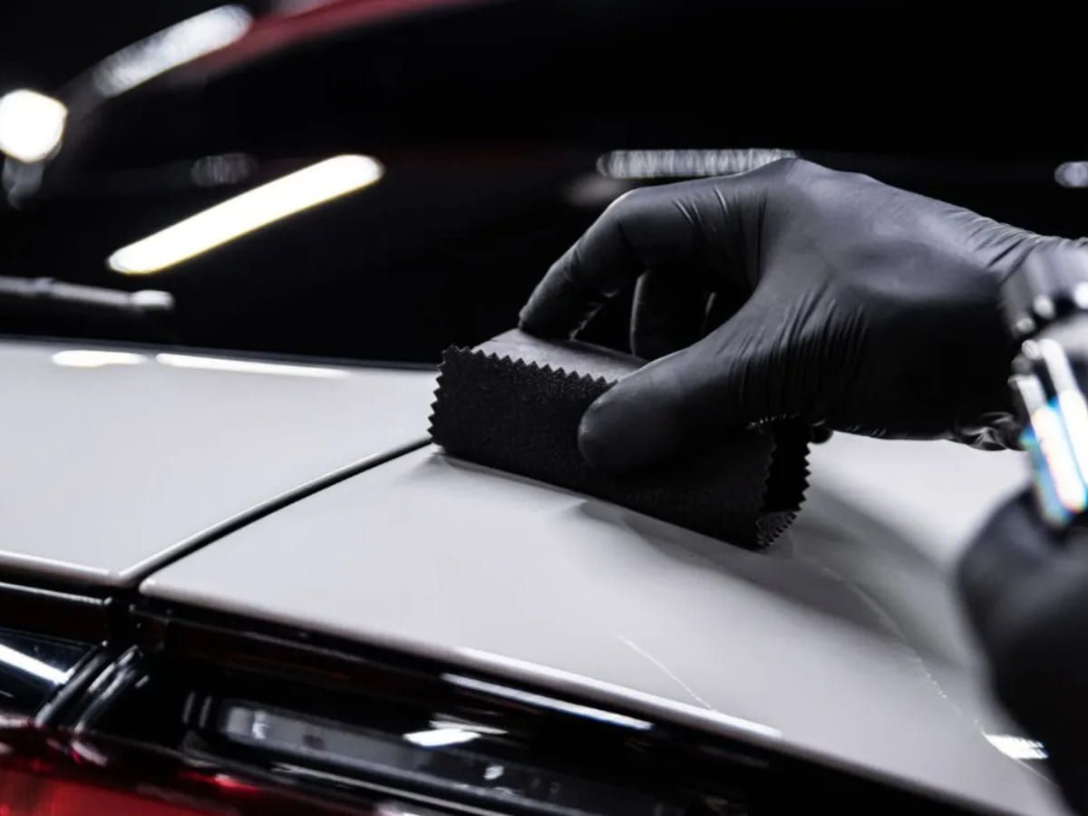 Technician applying ceramic coating to the white paint of a vehicle.