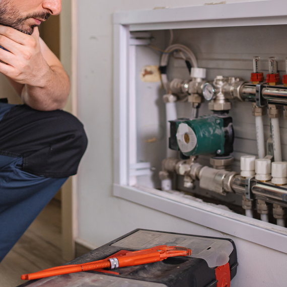 Electrician in blue shirt working on an electrical panel in a wooden-framed setting.