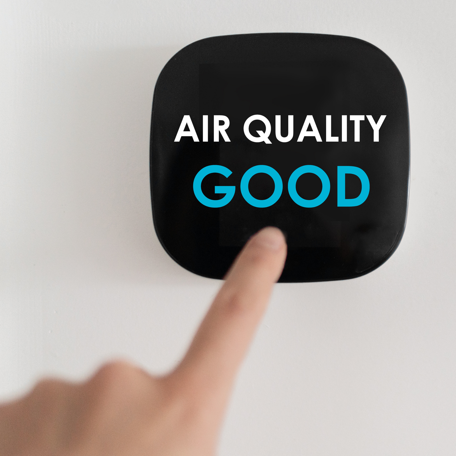 A finger pointing at a black air quality monitor with 