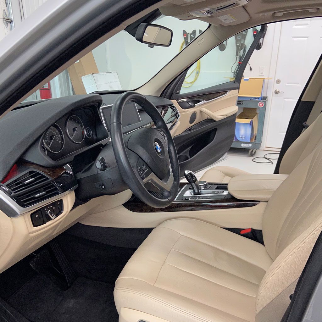 Interior of a tan and black BMW, driver's seat and dashboard visible.