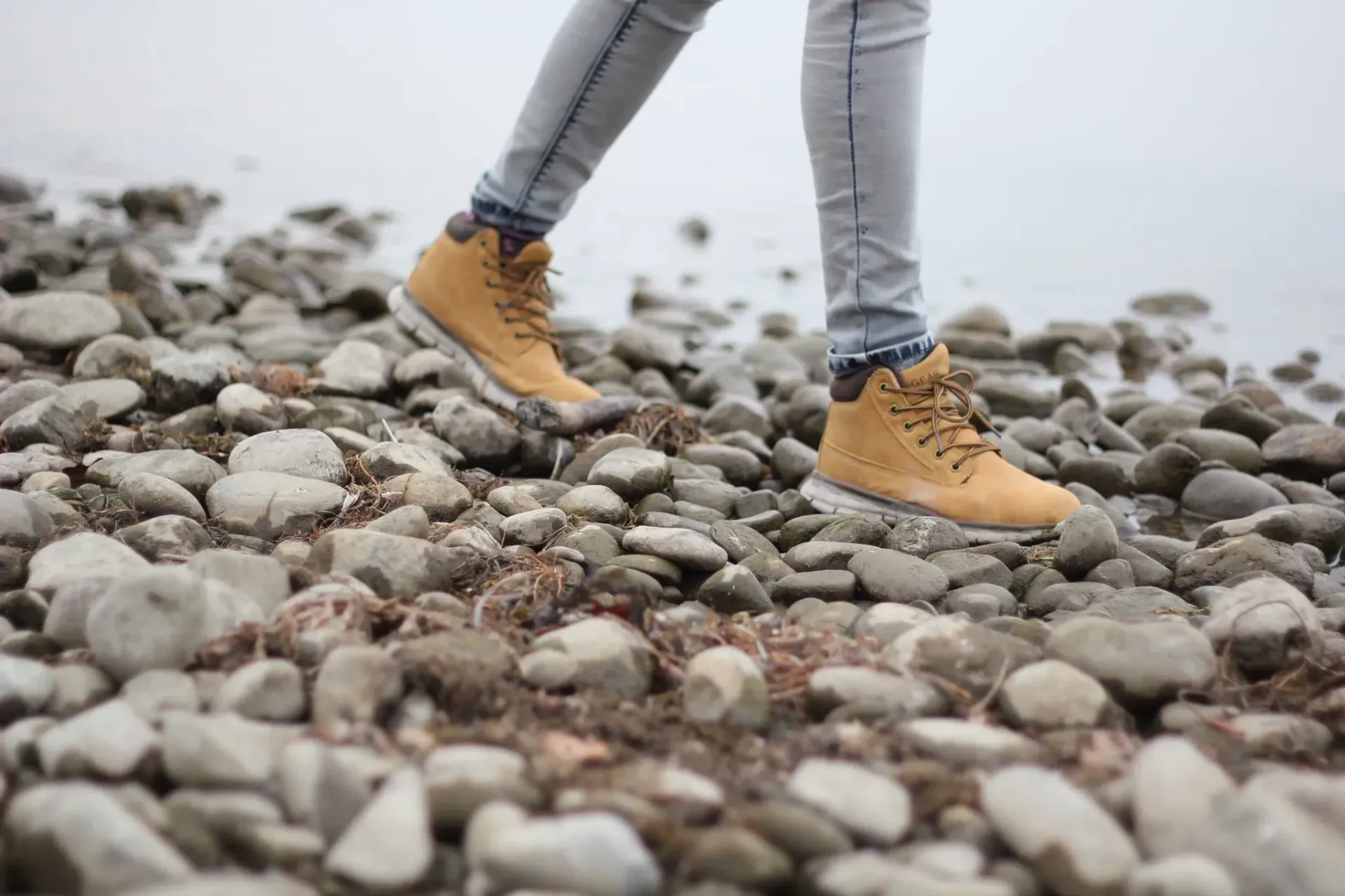 Person wearing tan boots walking on a rocky path