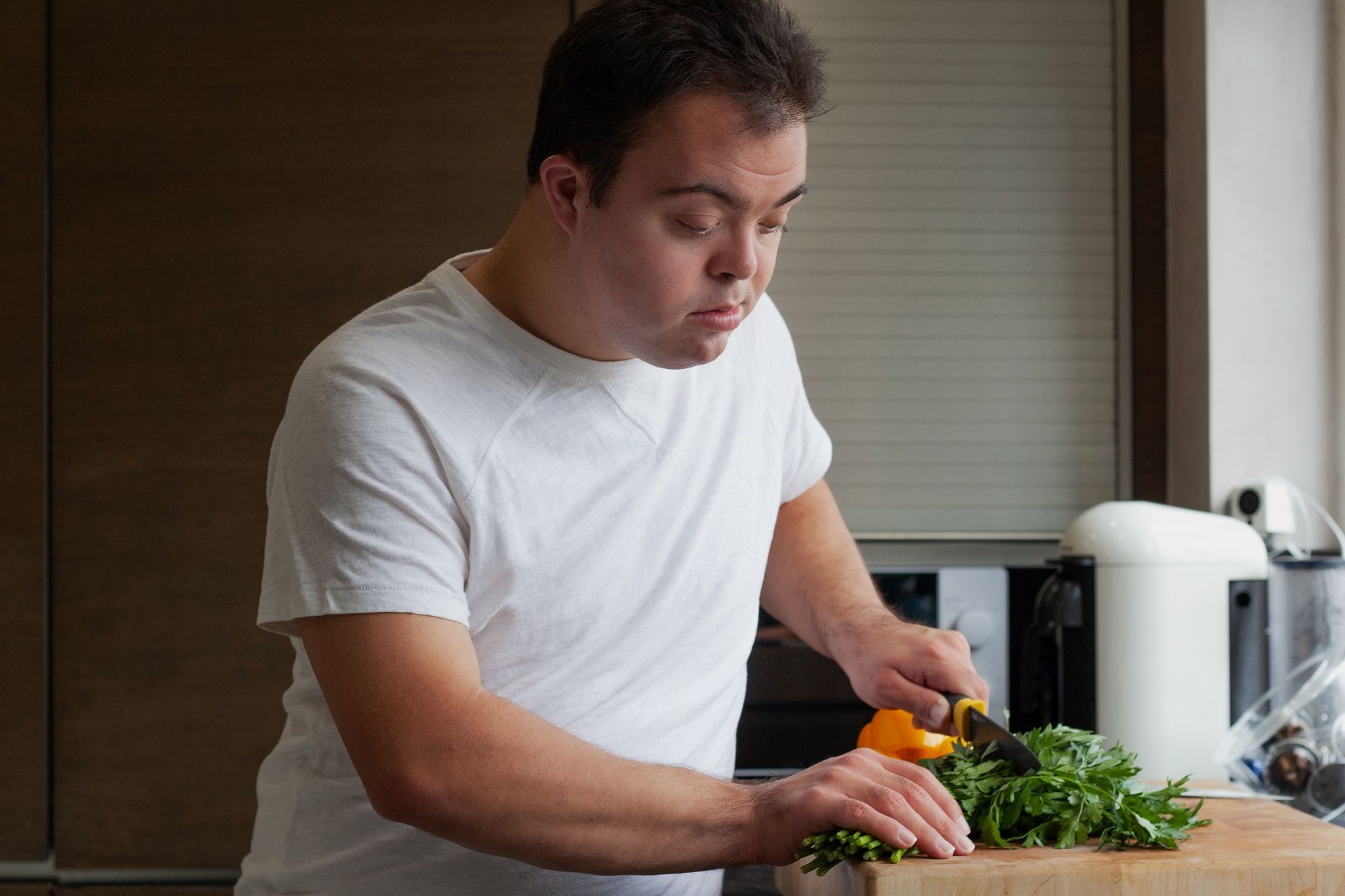 Man in a white shirt chopping vegetables on a kitchen counter