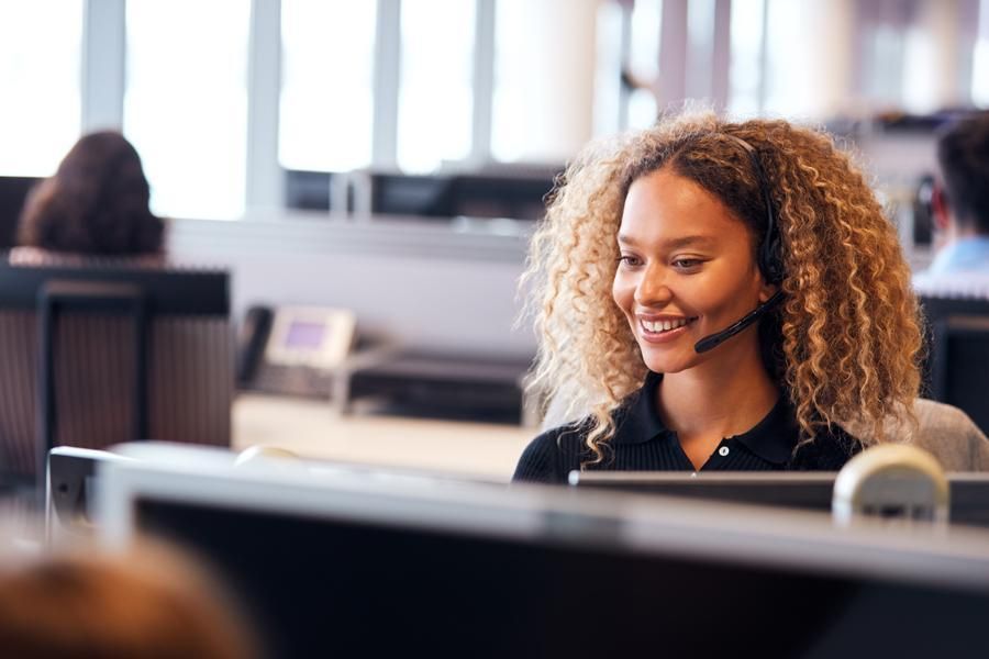 Smiling woman with curly hair using a computer in an office cubicle
