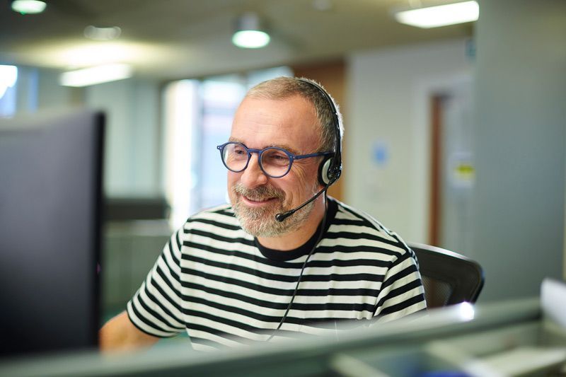 Man wearing glasses and headset smiling at a desk in an office