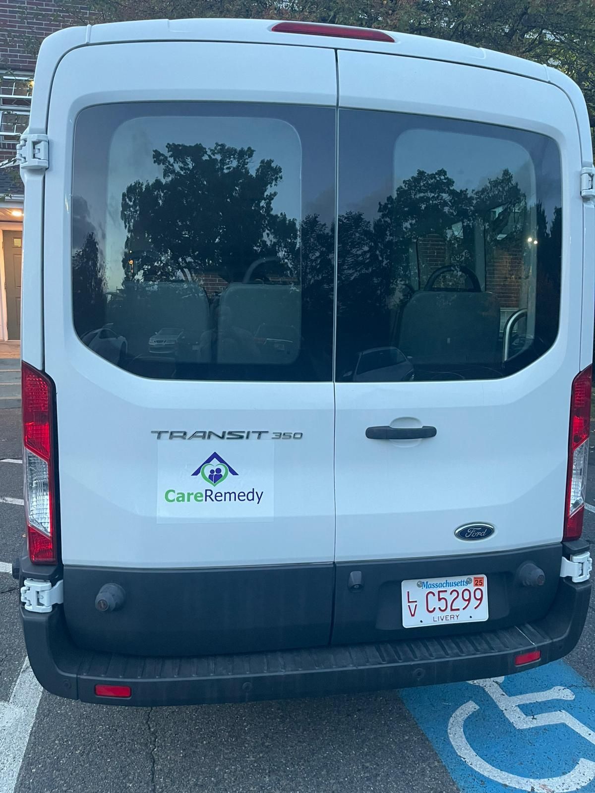 White Ford Transit van parked in a handicap space, rear view with CarMax logo and license plate visible