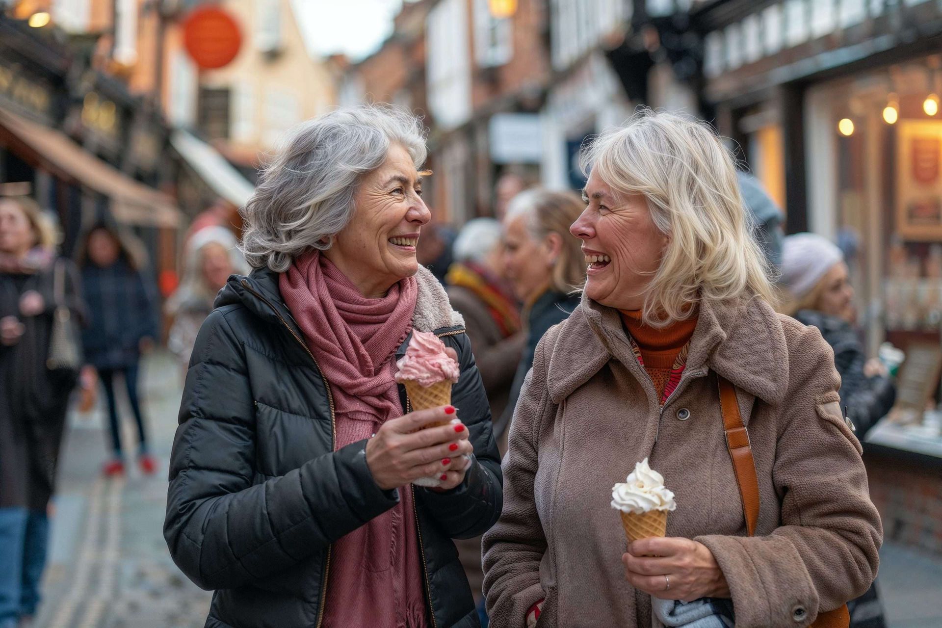 Two people chatting on a street, each holding ice cream, in a lively town center