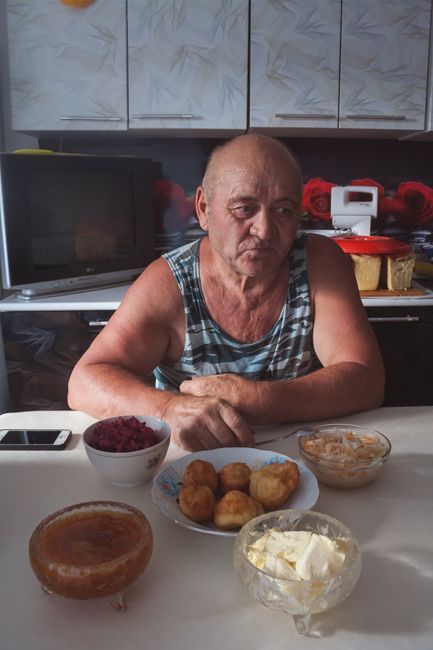 Older man eating a home cooked meal while a caregiver sits with him