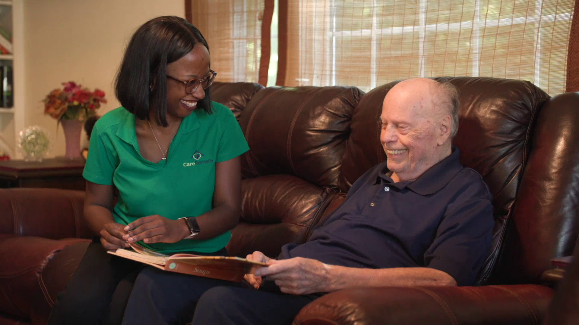 Home health aide sitting with an older adult with dementia at home in Massachusetts
