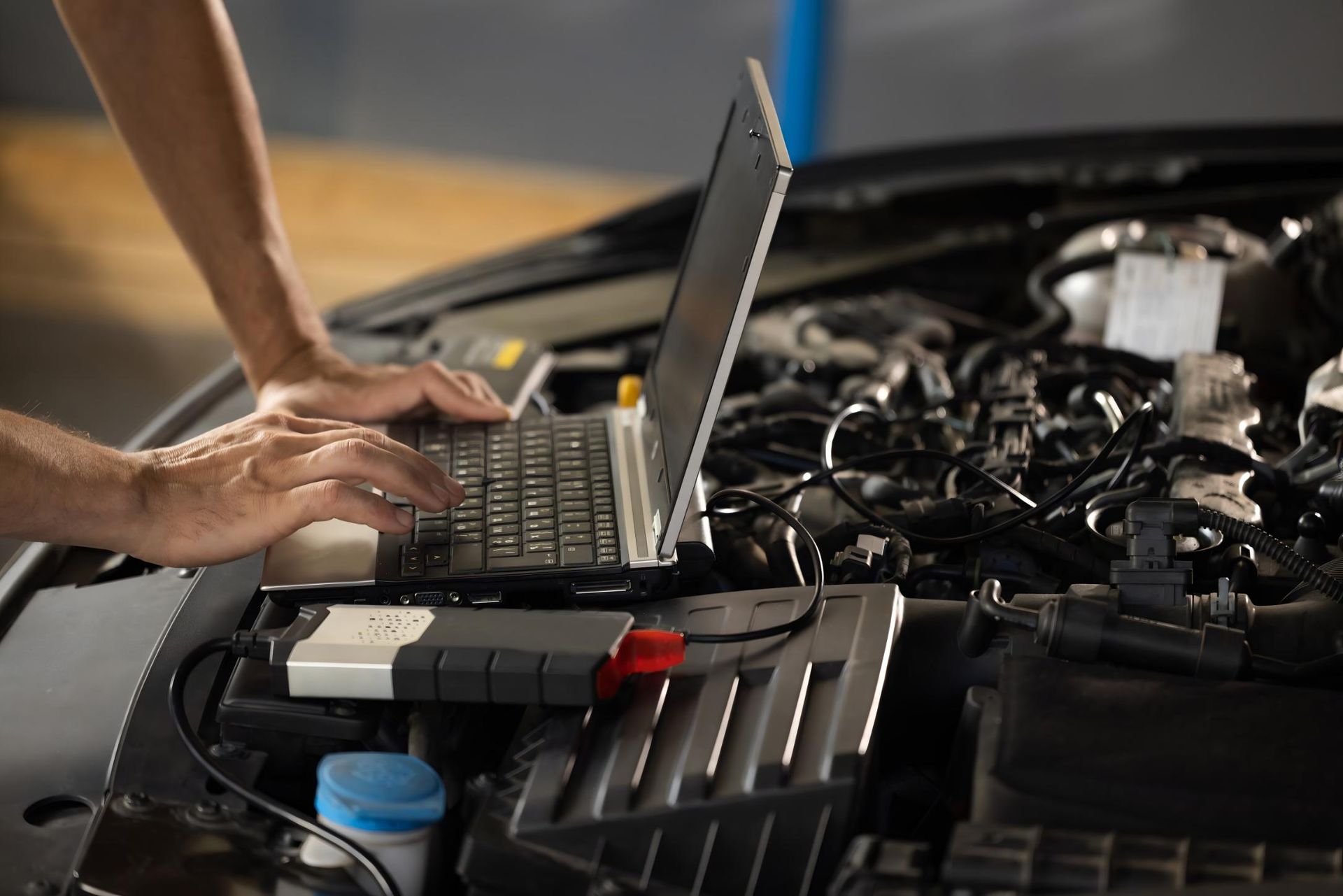 A Person is Using a Laptop Computer Under the Hood of a Car — CWC Auto Services In Ainslie, ACT