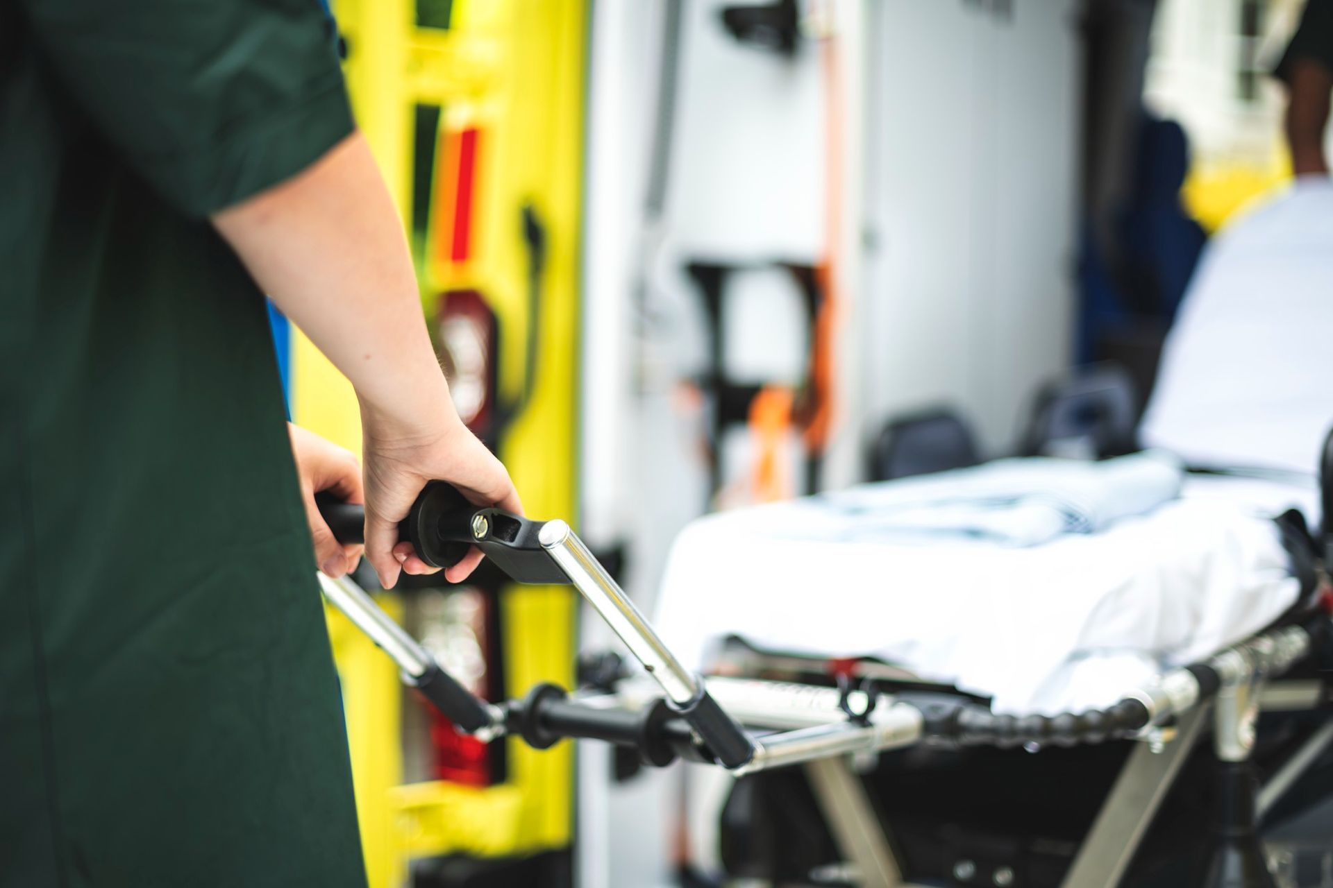 Técnico de emergencias médicas sosteniendo una camilla dentro de la ambulancia, preparándose para transportar a un paciente.