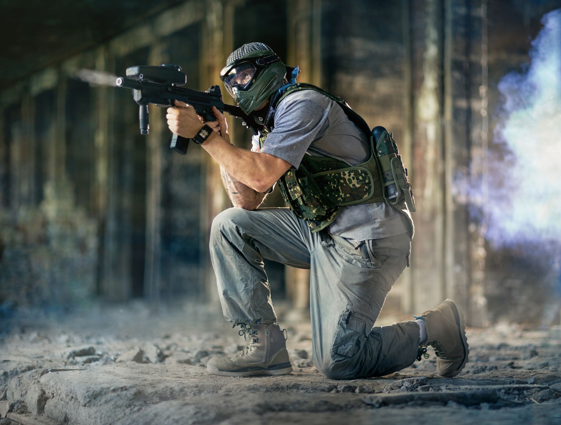 Joueur de paintball équipé d’un lanceur, d’un masque et d’un gilet tactique, évoluant dans un décor immersif.
