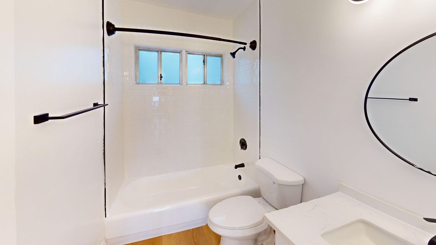 White accessible bathroom with walk-in shower, grab bars, toilet, and sink in a bright modern space