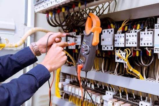 Technician testing wiring in an electrical control panel with a multimeter