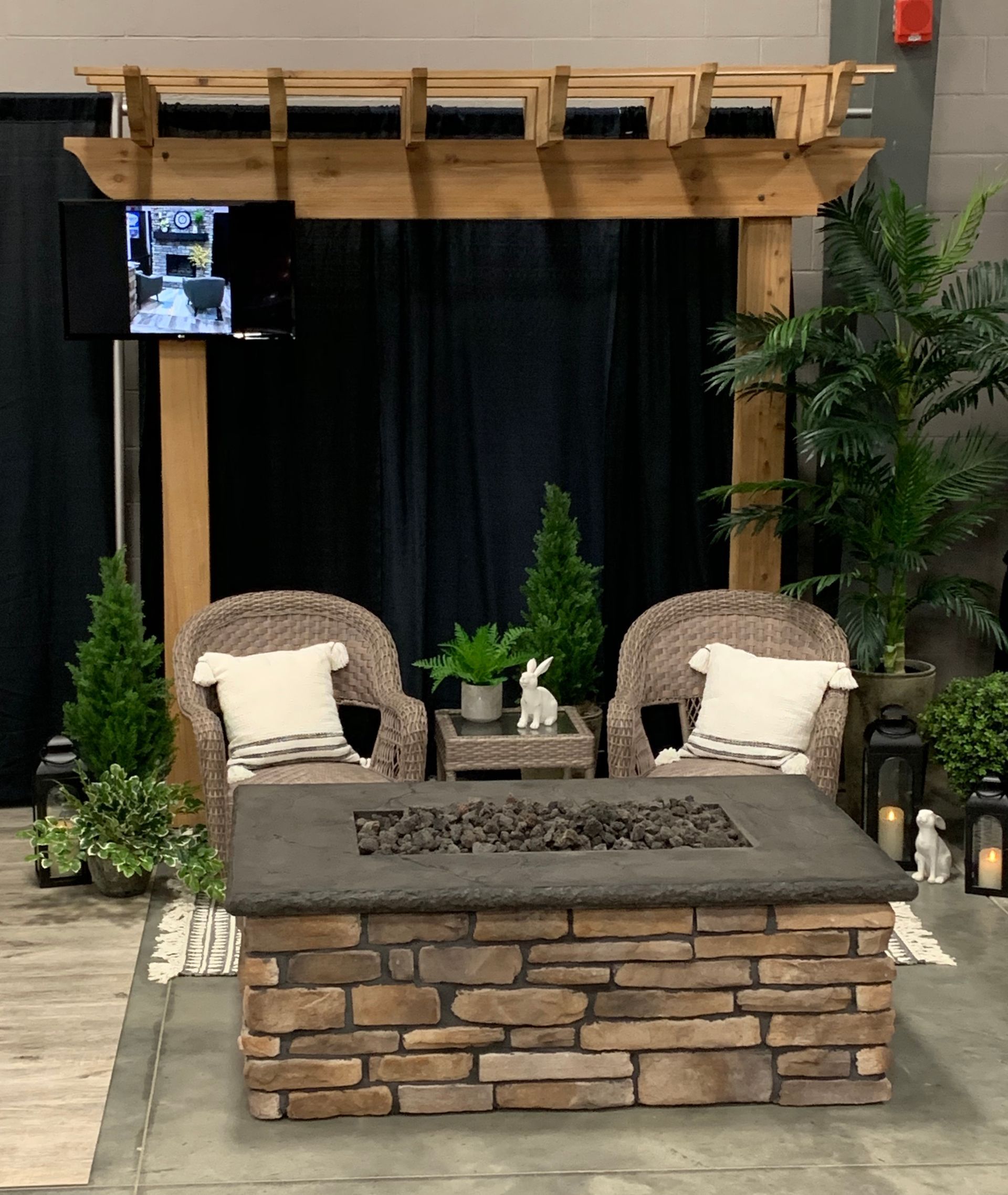 Outdoor living space with a fire pit, wicker chairs, and pergola backdrop.