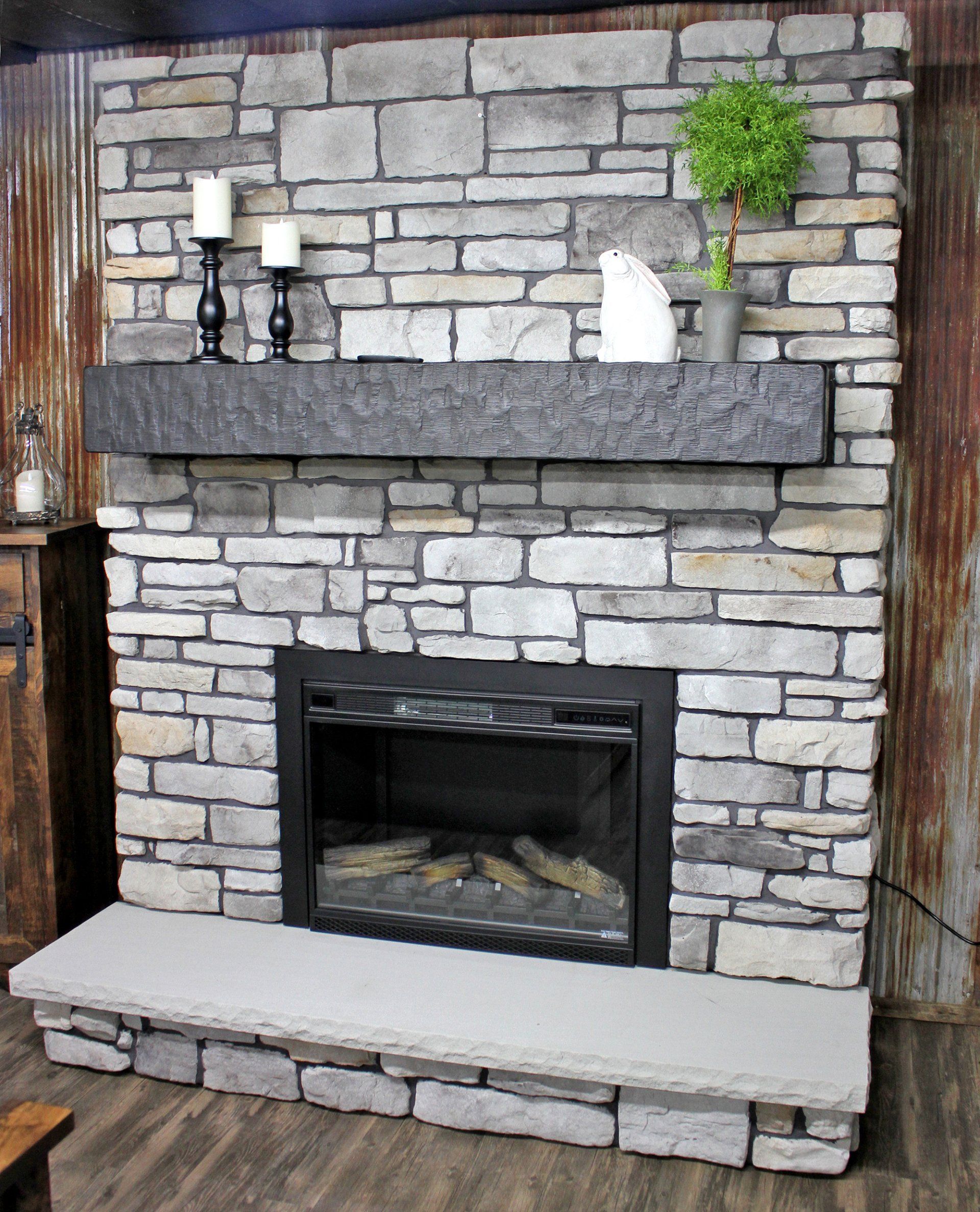 Stone fireplace with black mantel, candles, and a small potted plant.