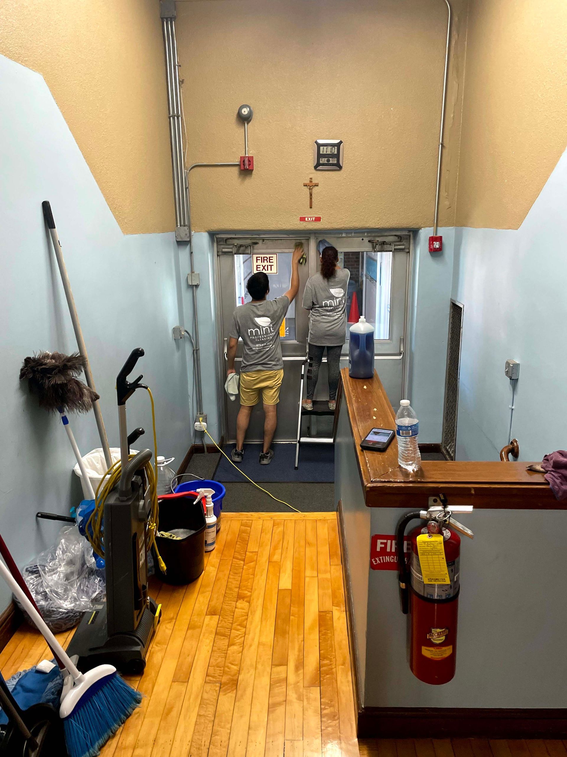 Day porter pushing a cleaning cart down a commercial hallway