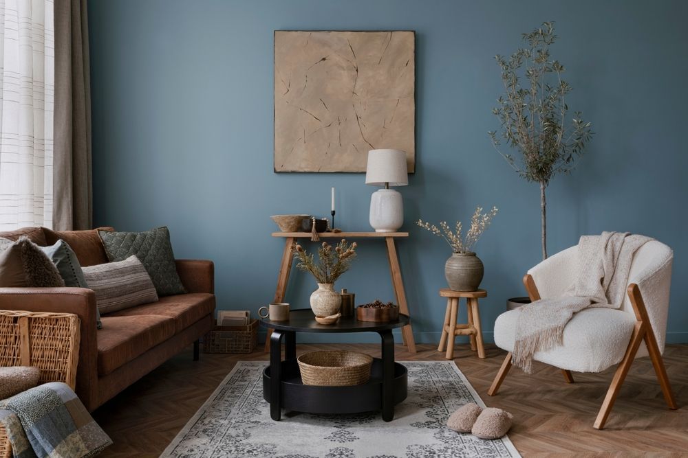 Cozy living room with blue walls, brown sofa, white lounge chair, and round coffee table