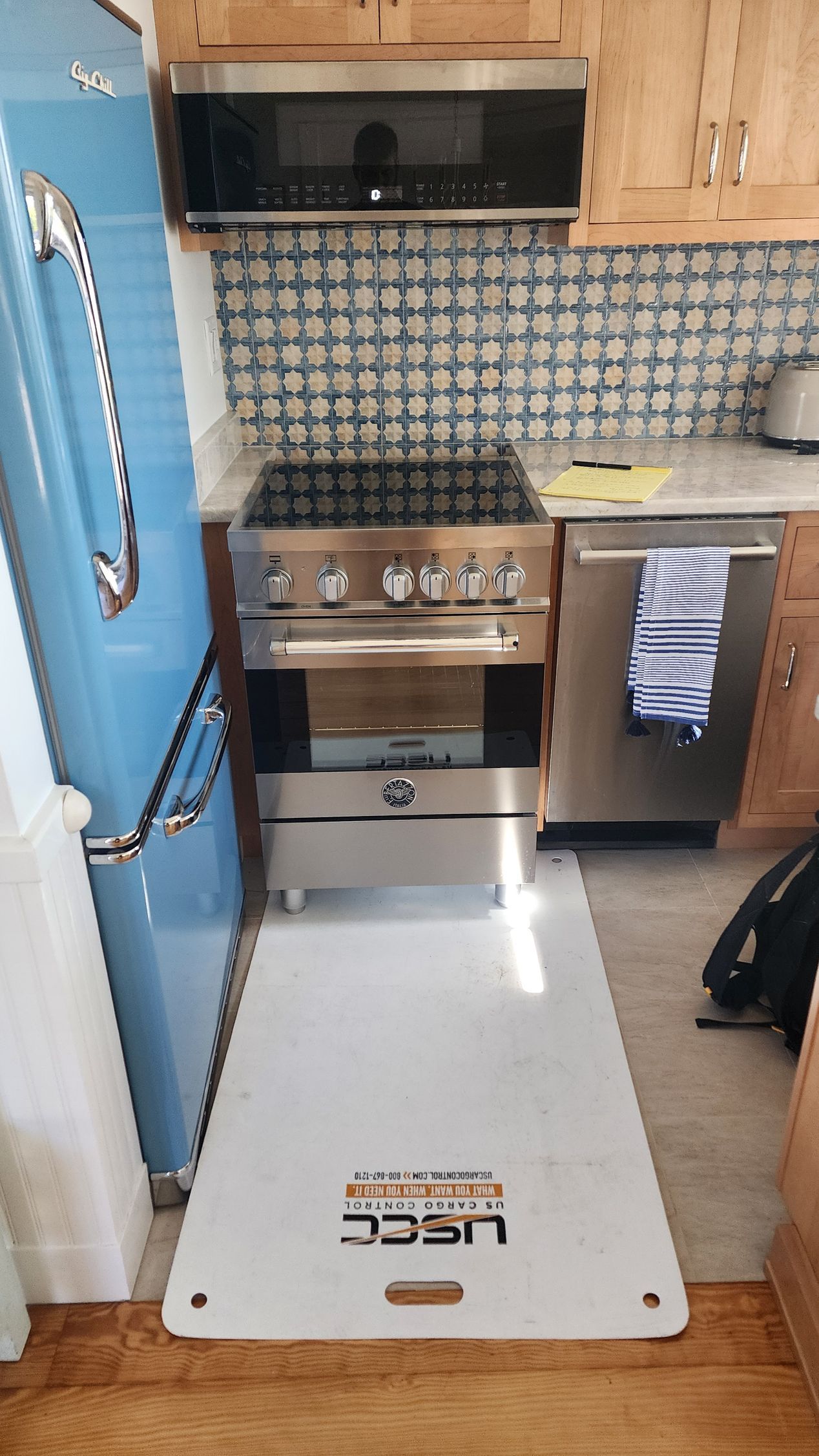 A modern kitchen features white cabinets, granite countertops, a stainless steel microwave and stove, and double windows.