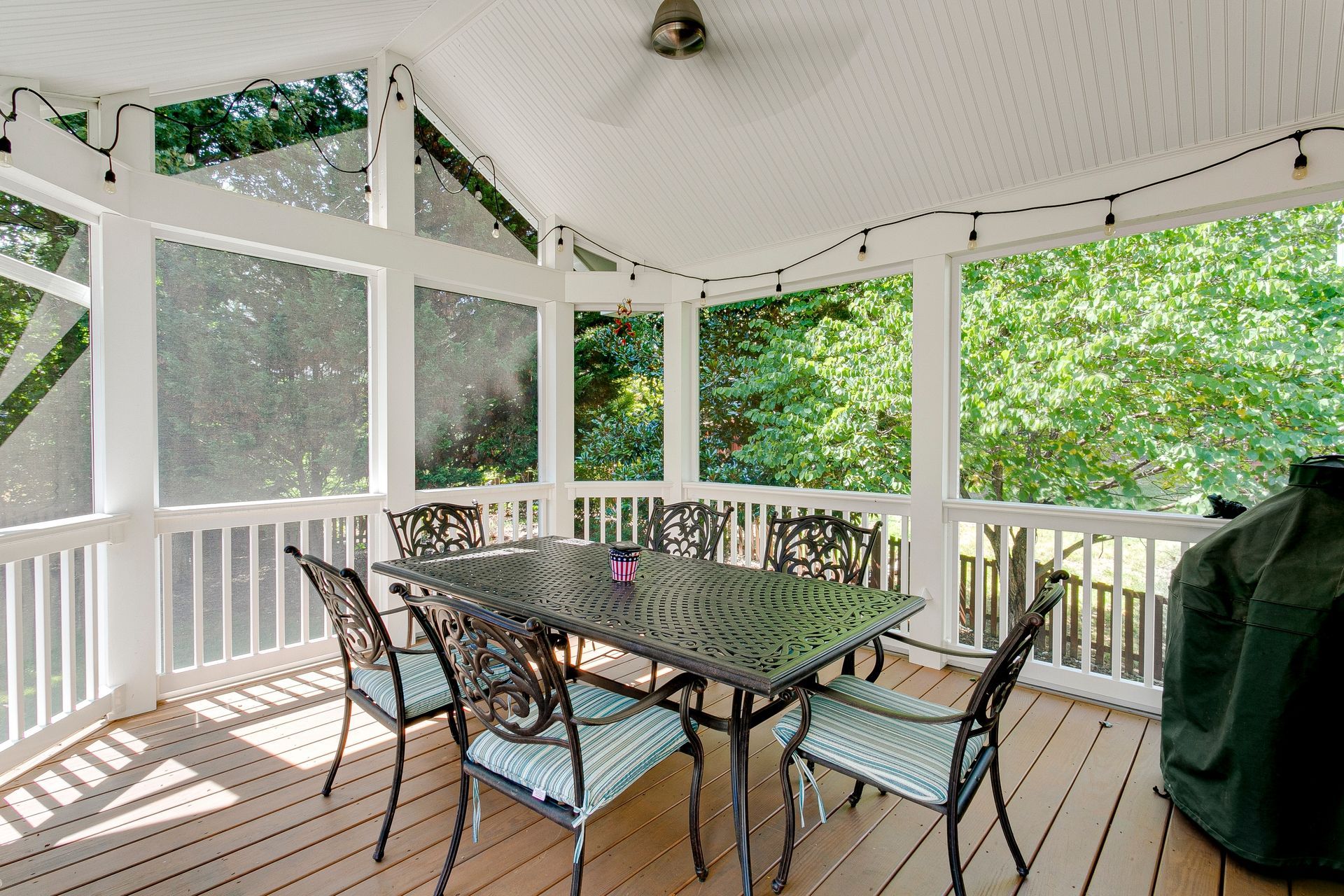 A screened in porch with a table and chairs