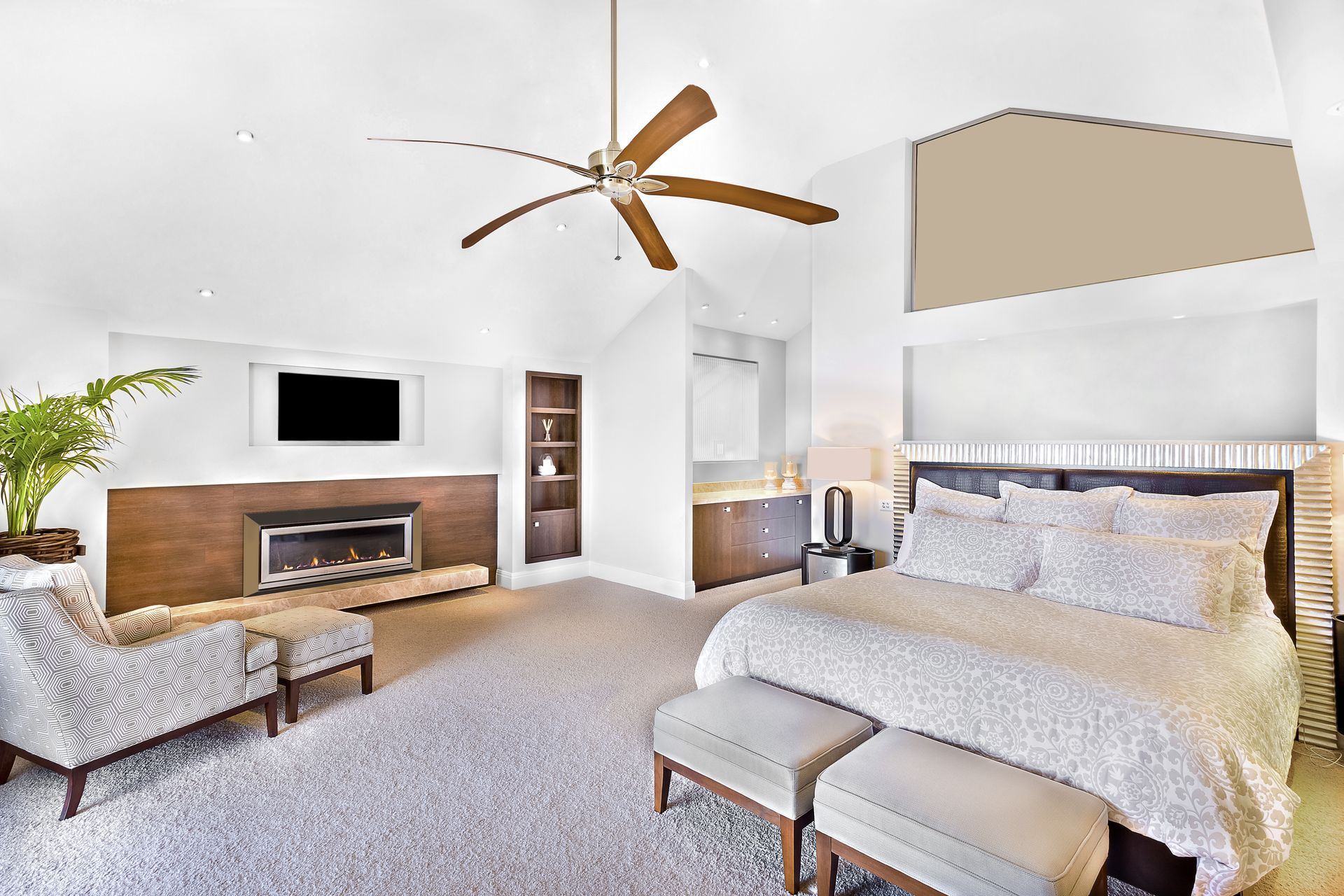 A bedroom with a bed , chairs , a fireplace and a ceiling fan.