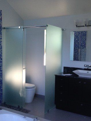 Bathroom with frosted glass shower enclosure, toilet, and vanity. Blue mosaic tile wall.