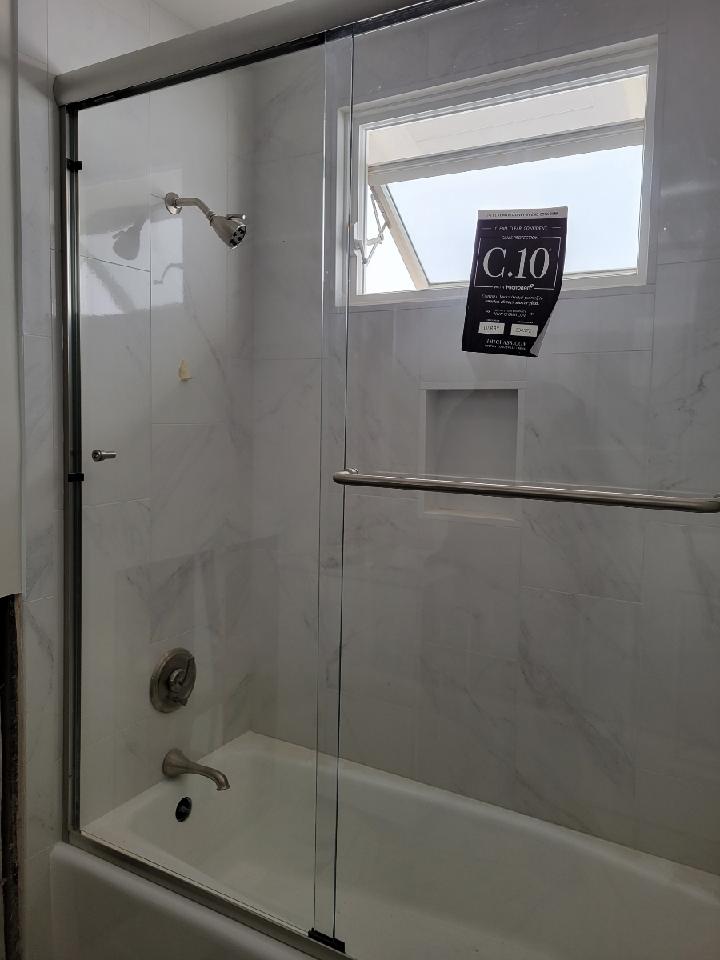 Bathroom with a white tub, shower with glass doors, and a small window.