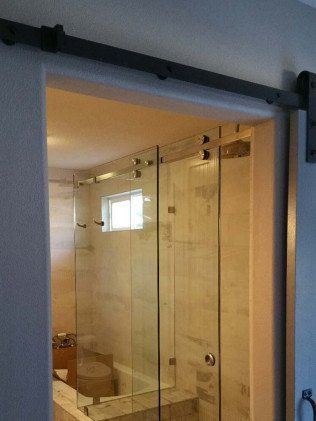 Barn door style shower door in bathroom with glass panels.