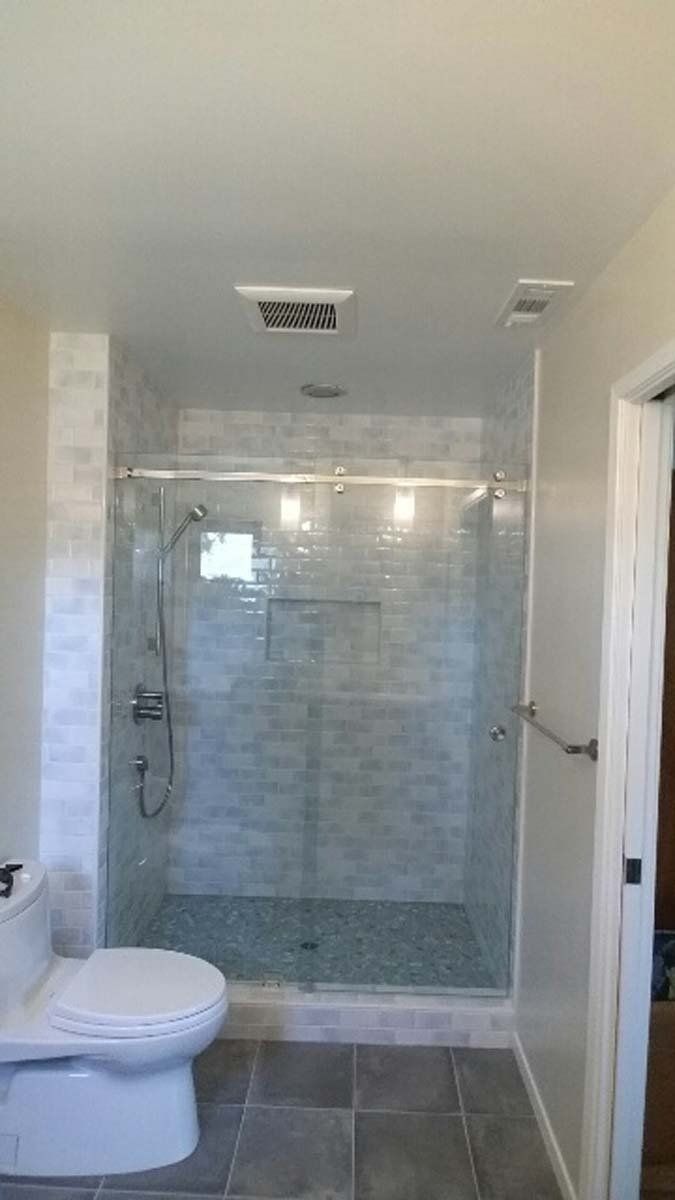 Bathroom with a glass shower, toilet, and gray tile floor.