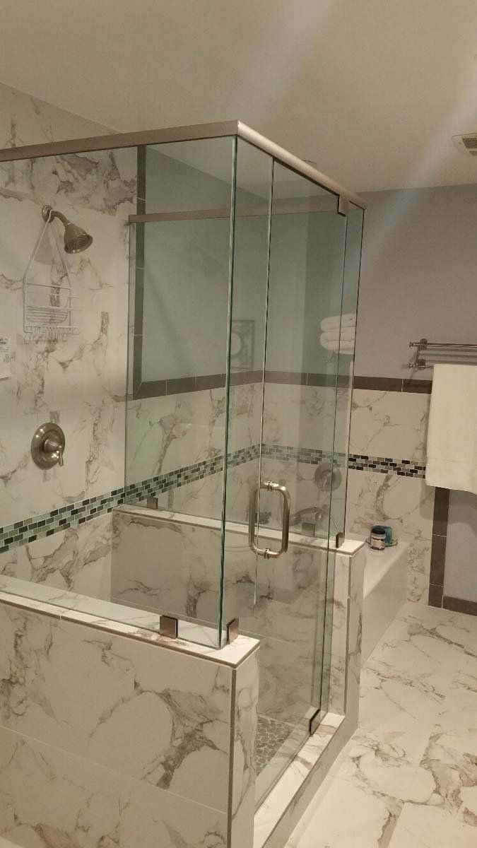 Glass shower enclosure with marble tile in a bathroom.