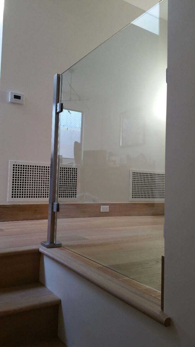 Glass railing with stainless steel posts on a wooden staircase.