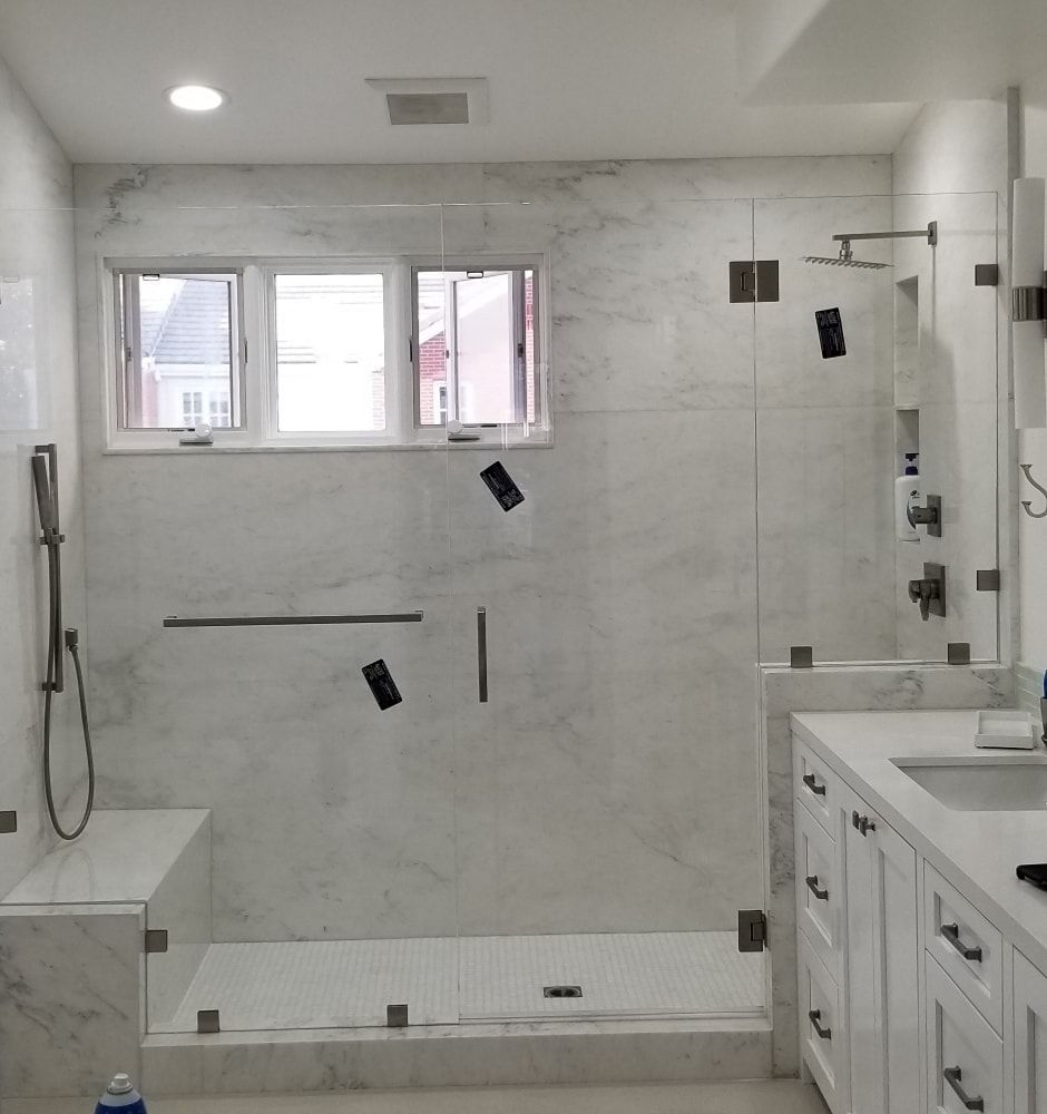 Modern bathroom with marble tile shower, window, and vanity.