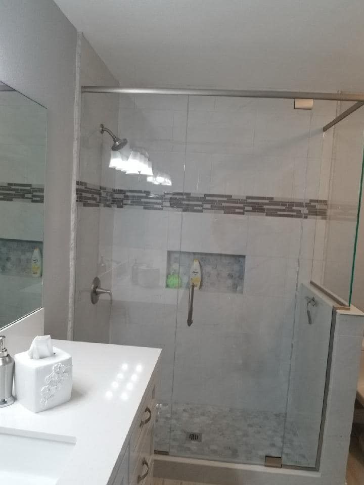 Modern bathroom with a glass shower, white vanity, and gray tile accents.