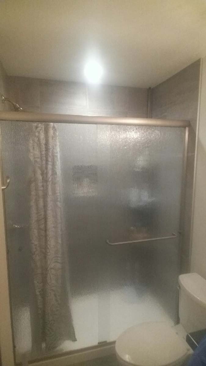 Bathroom with frosted glass shower doors, a toilet, and a shower curtain.