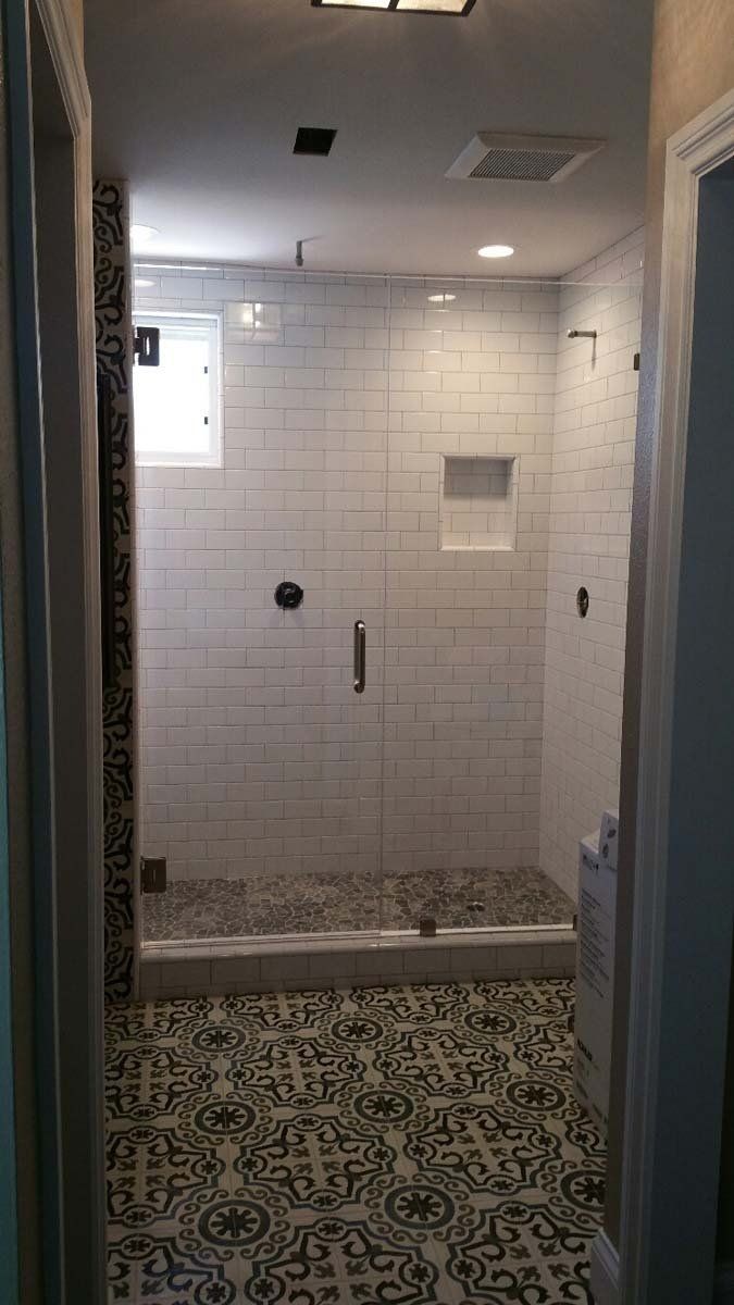 Bathroom with patterned tile floor, subway tile shower, and glass door.