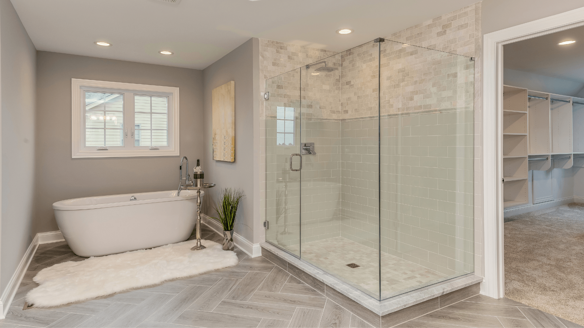 Modern bathroom with a white tub, glass shower, and walk-in closet access.