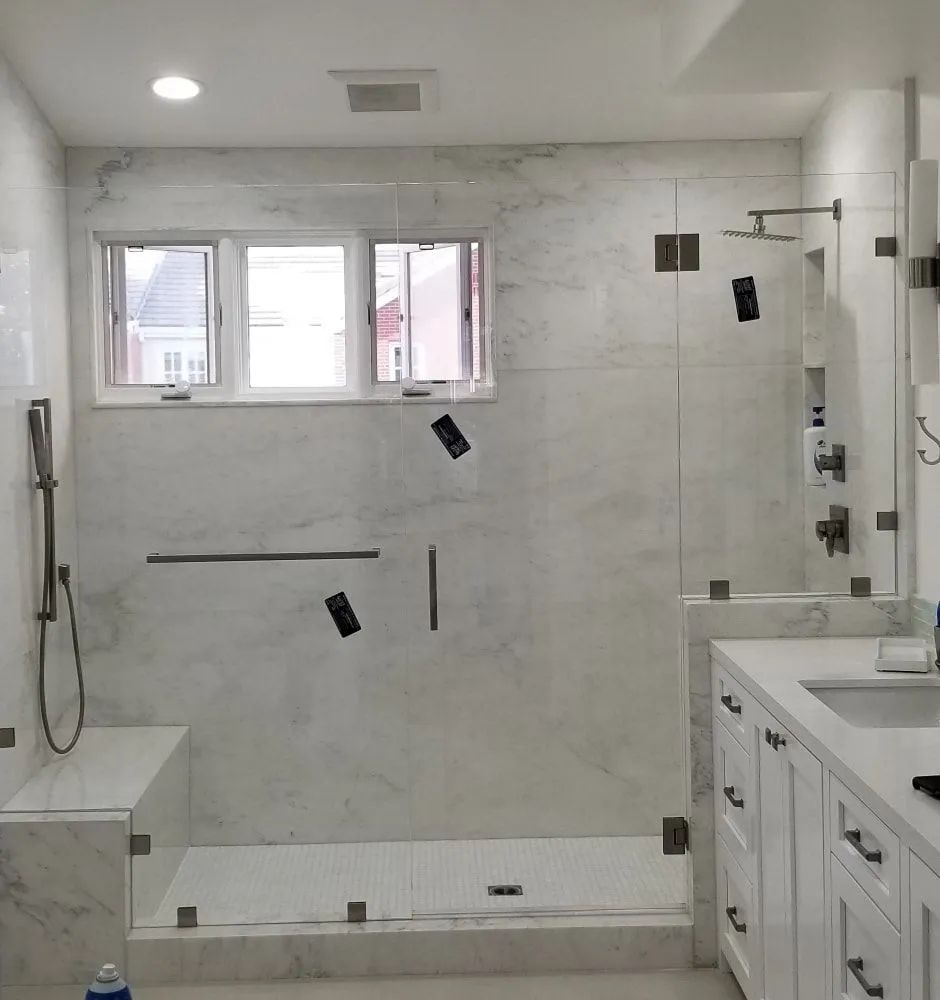 Modern white bathroom with glass shower, marble tile, and vanity sink