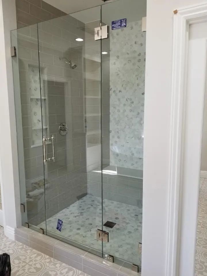 Glass walk-in shower with frosted tile accent wall in a bright bathroom