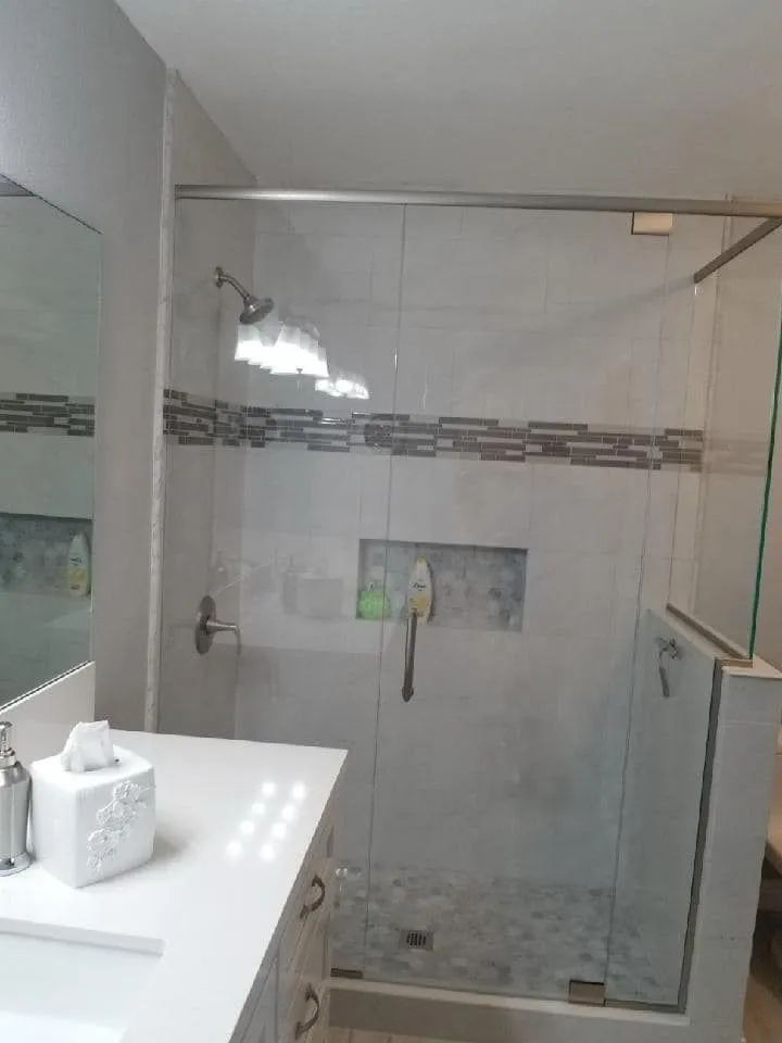 Bathroom with glass shower enclosure, tiled walls, and a white sink countertop.