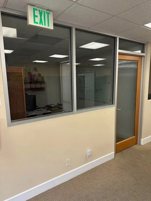 Office hallway with an EXIT sign, interior window, and wooden door.