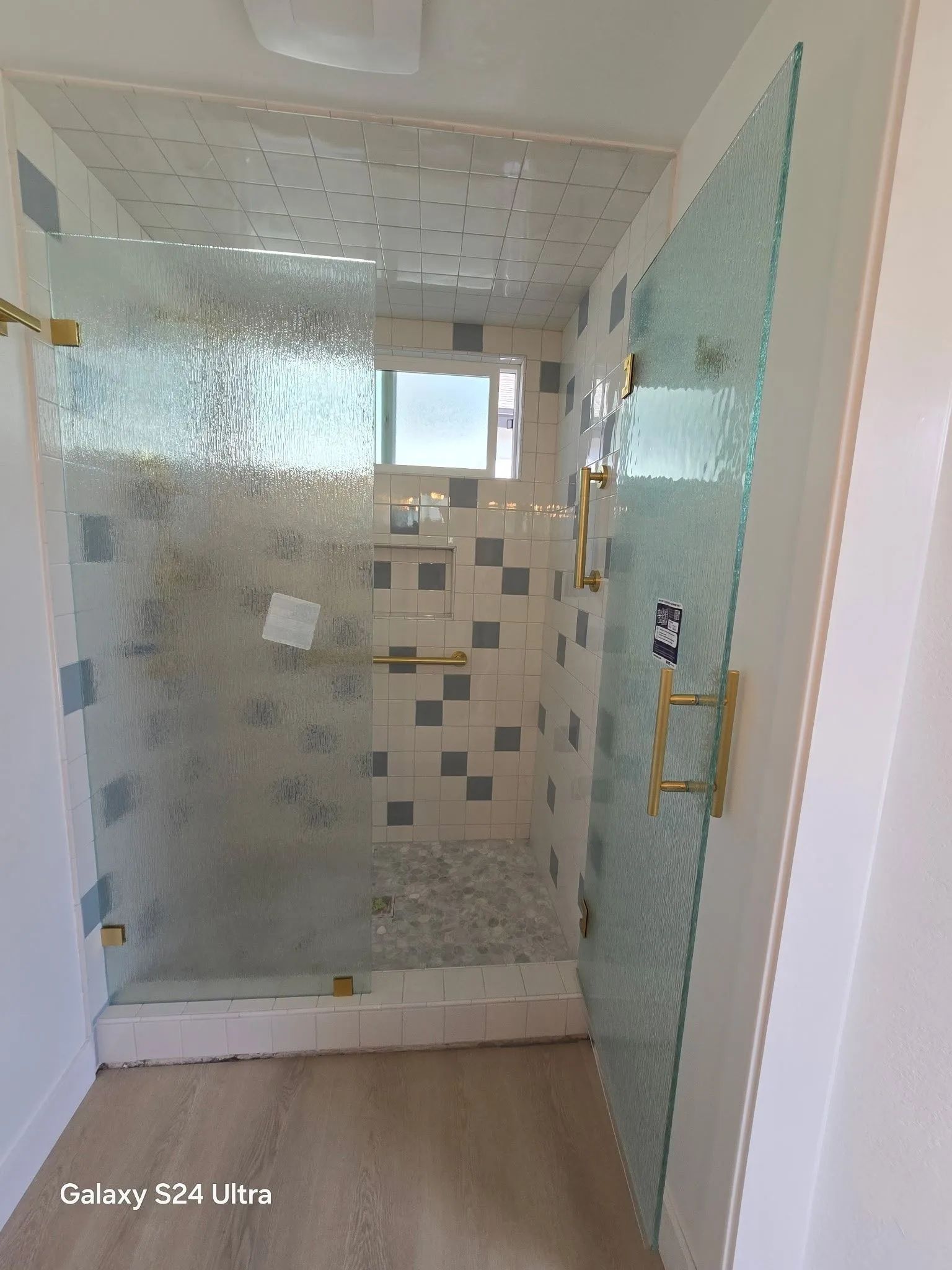 Bathroom with glass walk-in shower, tiled walls, and frosted glass door in a bright interior.