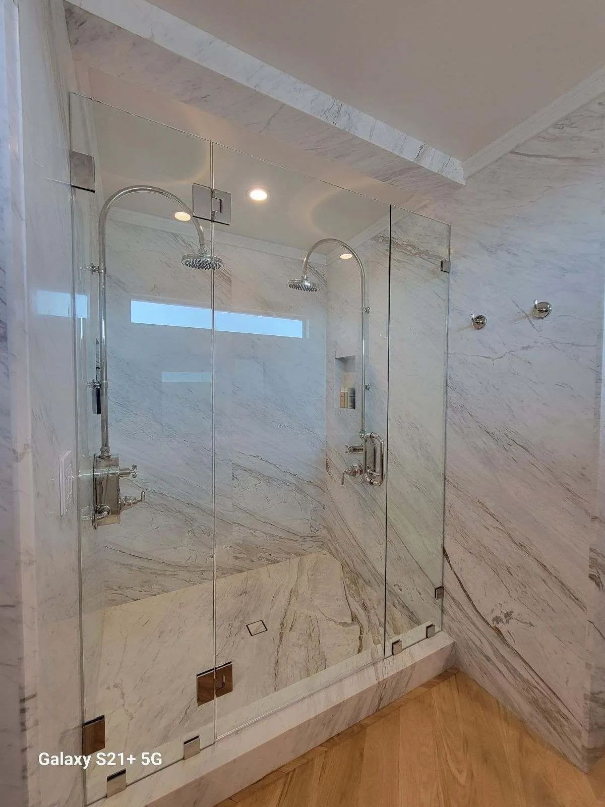 Modern marble-tiled bathroom with a glass-enclosed shower and chrome fixtures