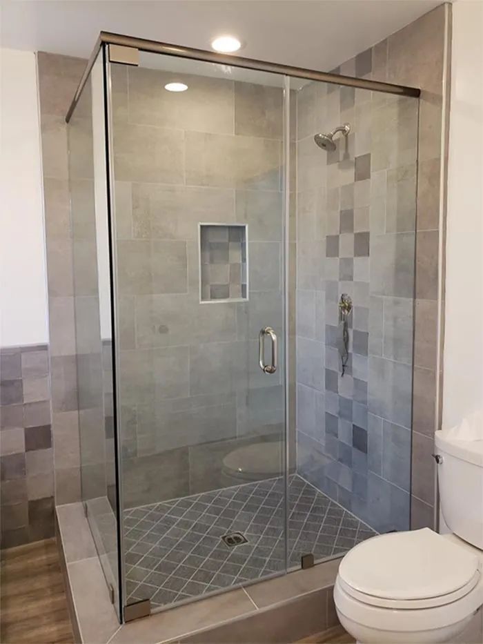 Glass-enclosed walk-in shower with gray tile and a white toilet beside it