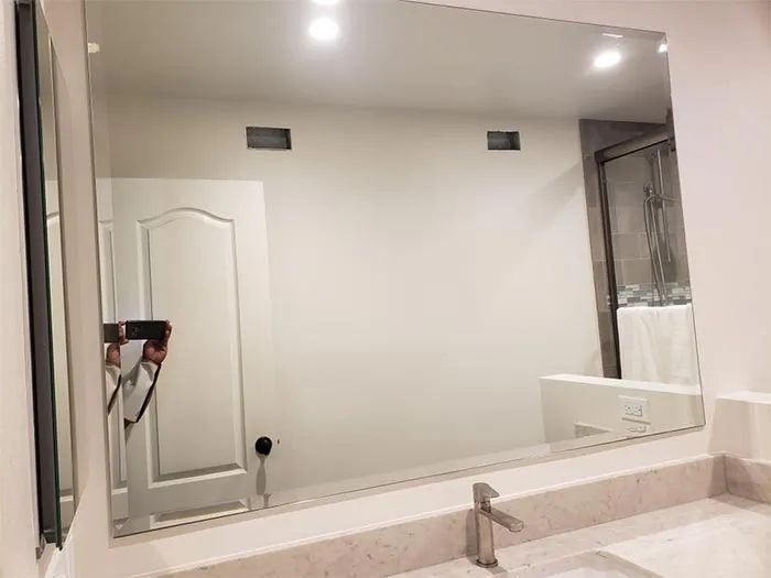 Modern bathroom with large mirror, white walls, vanity sink, and shower curtain.